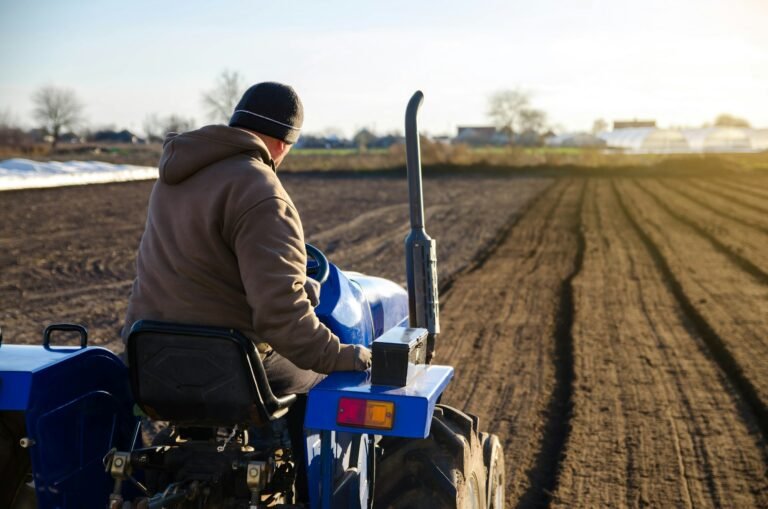 The tractor is cultivating the soil in the farm field.